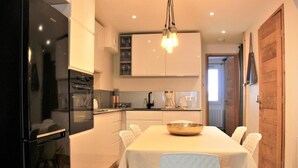 Une cuisine moderne avec une table à manger, des chaises et un luminaire suspendu.