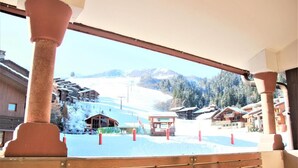 Un balcon en bois offrant une vue sur une station de ski enneigée.