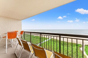 Een balkon met stoelen en uitzicht op het strand.