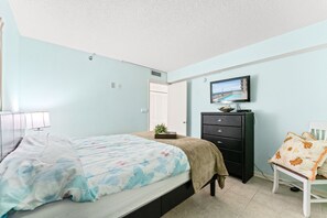 Een slaapkamer met een bed, een dressoir, een stoel en een televisietoestel.