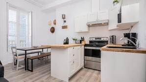 A modern kitchen with white cabinetry, a wooden countertop, and a built-in oven. - Manoir des Remparts 3 Bdrm Oasis (Québec City)