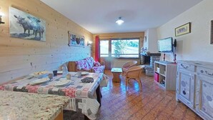 A cozy, well-lit room with a dining table set for two, a sofa, and a television. - 1st floor, view ski slopes, balcony, fireplace or stove, tv, 45m², Le Grand Bornand (Le Grand-Bornand)
