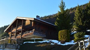 Una cabaña de madera con balcón, rodeada de nieve y árboles.