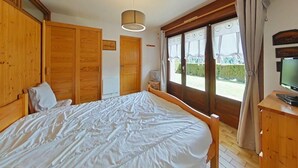 Un dormitorio con una cama grande, un armario de madera, un televisor y una ventana con cortinas.