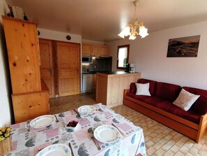 Cozy living space with dining area and living room, featuring a table set for four and a comfortable seating area.