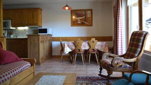 Uma sala de estar acolhedora com um sofá de madeira, uma cadeira de balanço e um espaço de jantar com mesa e cadeiras.