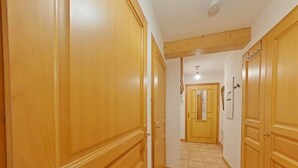 Um corredor com portas de madeira e piso de azulejos.