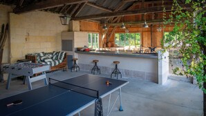 Ein rustikales Holzinterieur mit Tischtennisplatte, Kicker und Barhocker.