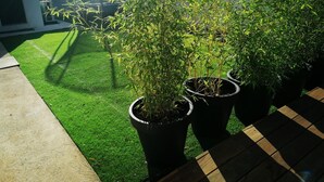 Een terras met kunstgras, plantenbakken en een houten vlonder.