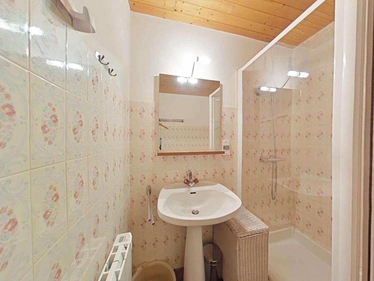 Ein Badezimmer mit Waschbecken, Spiegel, Dusche und gefliesten Wänden.