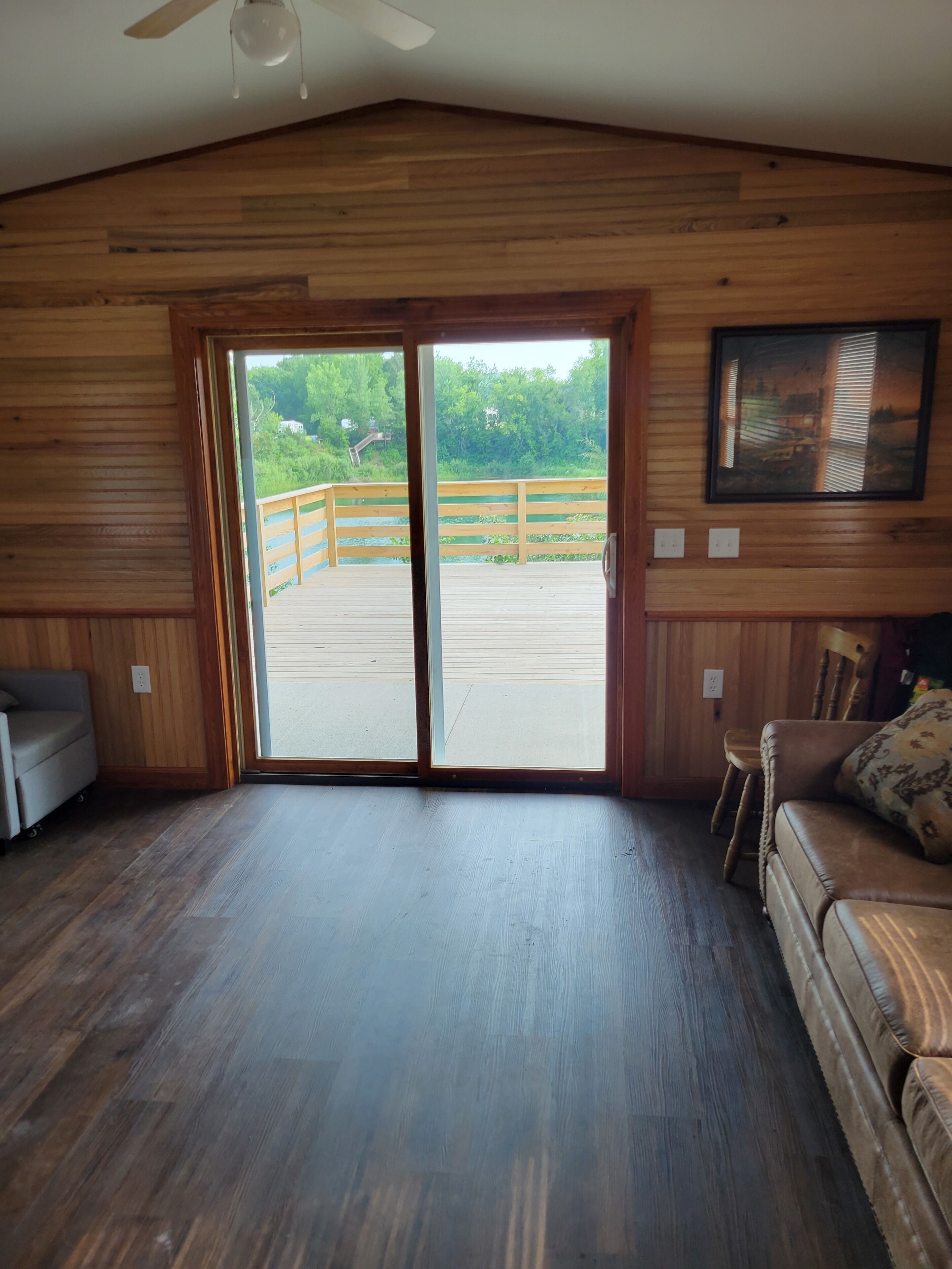 A room with wooden walls and a large sliding glass door leading to an outdoor deck.