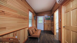 A cabin interior with a wooden bench, a door, and a hallway leading to another room. - Quaint Lakeview Cabin  (Wadena)
