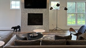 Un salon avec un téléviseur à écran plat fixé à un mur texturé, un canapé, une table basse et un lampadaire.