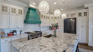 A kitchen with white cabinetry, a large island, a stainless steel refrigerator, and a green hood. - Luxurious Spacious Chateau on Table Rock Lake with Hot Tub (Ridgedale)