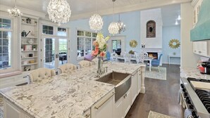 A spacious kitchen with a large island, white cabinetry, and a chandelier. - Luxurious Spacious Chateau on Table Rock Lake with Hot Tub (Ridgedale)