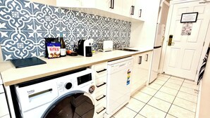 A compact kitchen with a washing machine, a coffee maker, and a toaster. - Brisbane CBD Studio: Modern Comfort Great Location (Brisbane City)