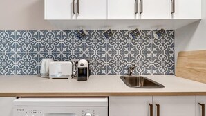 A kitchen with white cabinets, a patterned backsplash, a coffee maker, a toaster, and a dishwasher. - Brisbane CBD Studio: Modern Comfort Great Location (Brisbane City)