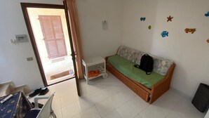 Une petite pièce propre, avec un lit, une chaise, une table et une armoire.