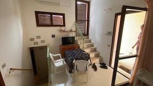 Une chambre à coucher de taille modeste, comprenant un lit, un bureau, une chaise, un téléviseur et un escalier menant à un balcon.