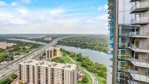 Un immeuble de grande hauteur doté de nombreux balcons donnant sur une rivière et une autoroute.