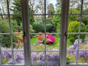 A view through a window with a garden in front, featuring various plants and flowers. - Little Robin Gate (Bournemouth)