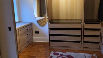 A walk-in closet with wooden shelving, a mirror, and a bench.