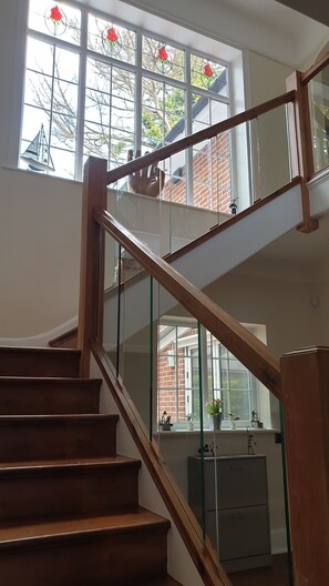 A wooden staircase with glass railings leading to an upper floor. - Little Robin Gate (Bournemouth)