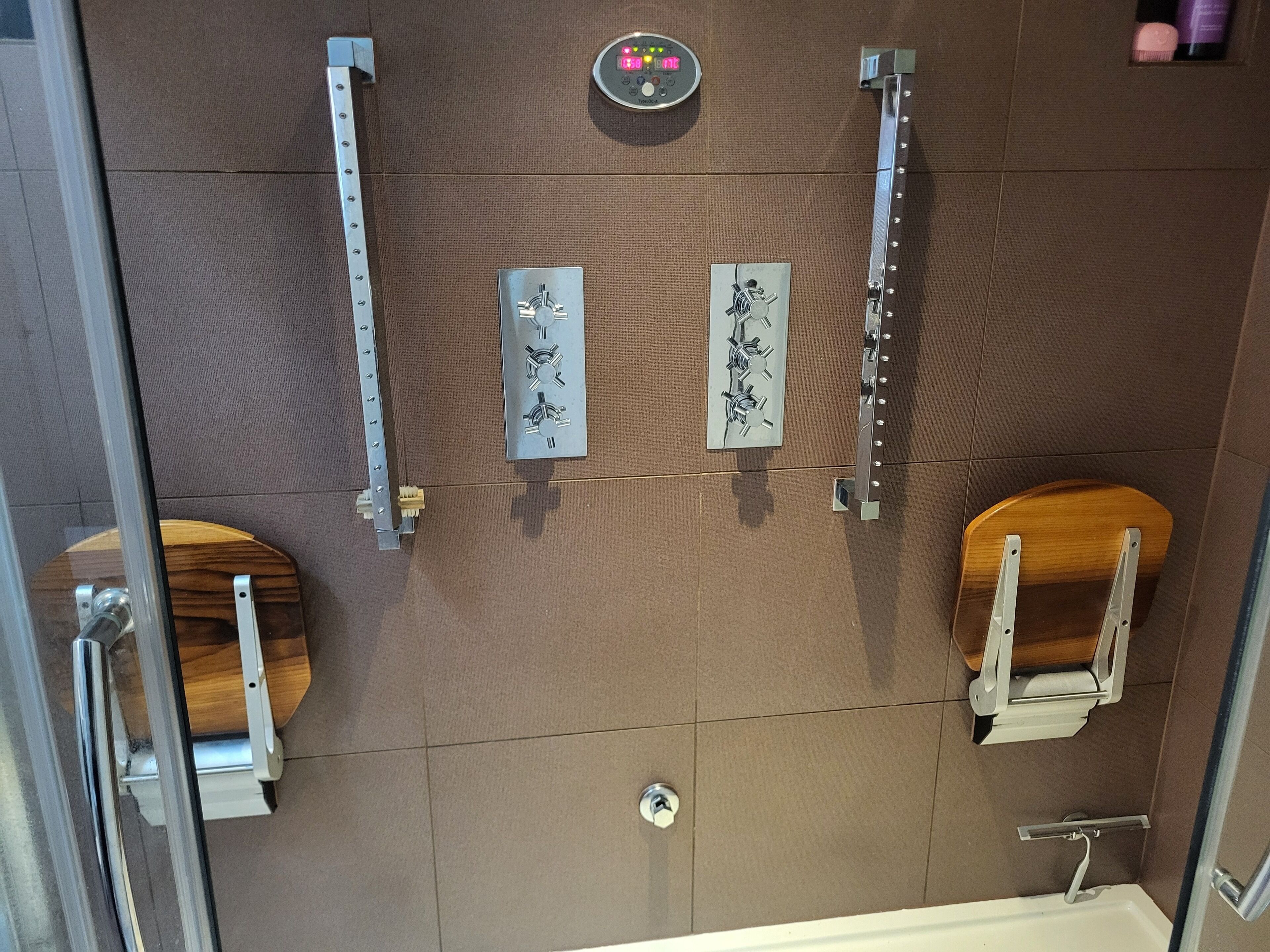 Un baño moderno con ducha, inodoro y panel de control sobre la ducha.