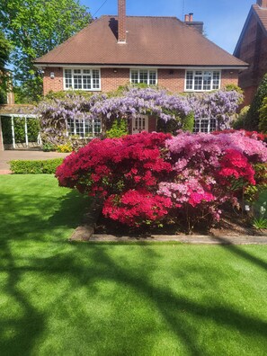 Una casa de ladrillo con un césped cuidado y flores coloridas.