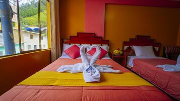 Habitación de hotel con dos camas, cada una con ropa de cama roja y una manta amarilla. Se aprecia una ventana con vistas a edificios y zonas verdes.
