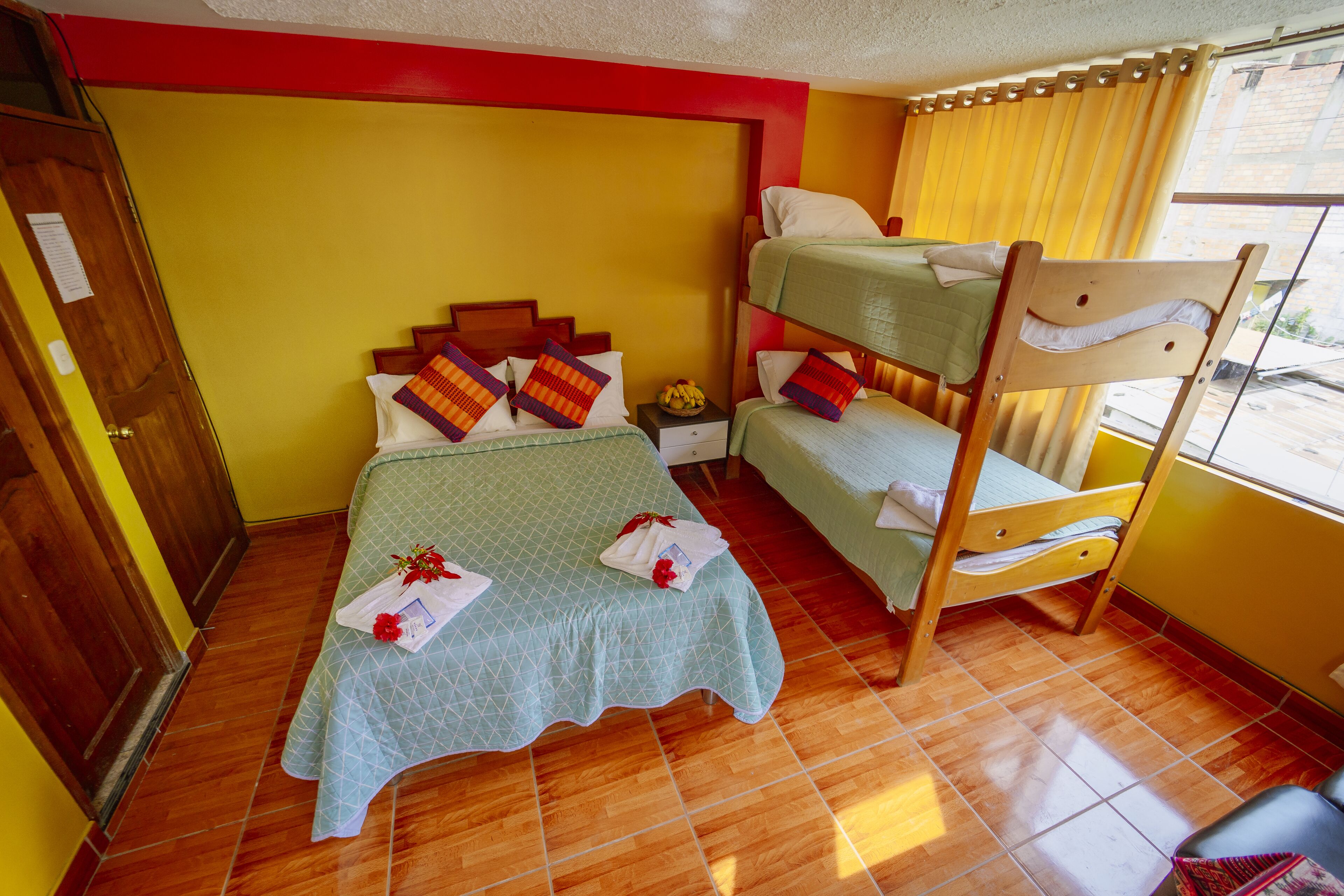 A room with a bunk bed, a wooden wardrobe, and a tiled floor.