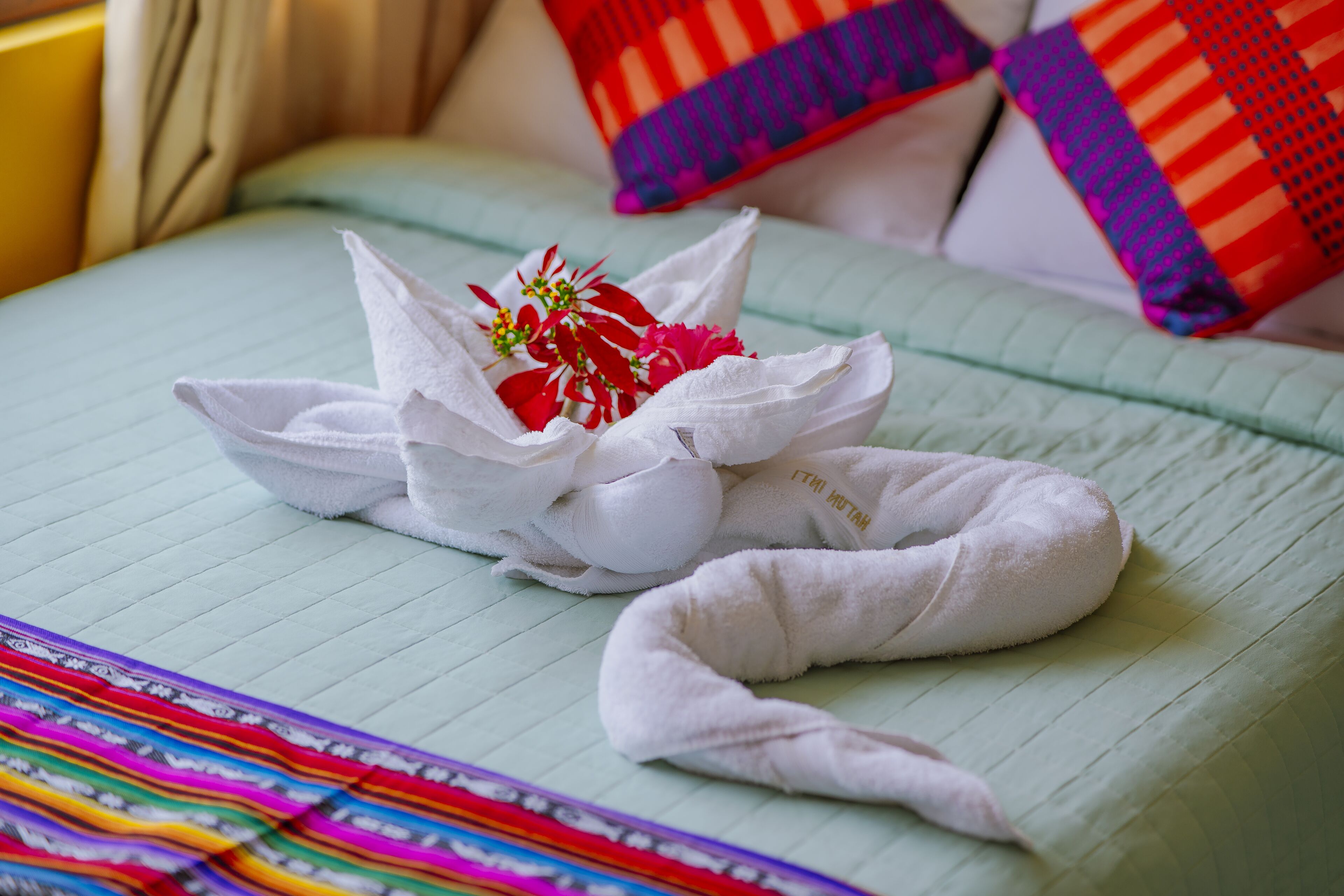 A neatly made bed with a floral pillow and a towel.