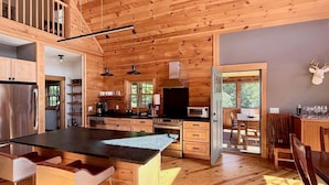 Un interno di una baita in legno con cucina, zona pranzo e un'isola grande.