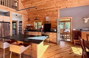 Interior de una cabaña de madera con cocina, comedor y una isla grande.