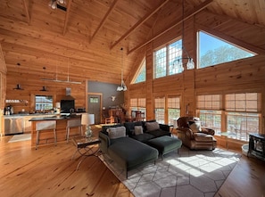 A spacious log cabin interior with a kitchen, dining area, and seating area.