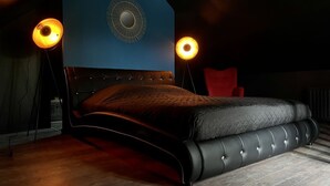 A modern bedroom with a tufted headboard, a large bed, and two floor lamps. - LoveRoom by Gîtes d'Armor (Plelo)