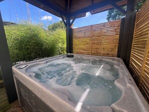A hot tub with a wooden deck and a wooden fence in the background. - LoveRoom by Gîtes d'Armor (Plelo)