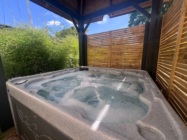 A hot tub with a wooden pergola overhead, surrounded by lush greenery. - LoveRoom by Gîtes d'Armor (Plelo)