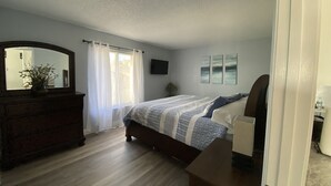 Ein Schlafzimmer mit einem Holzkapuzen, einem Bett mit gemusterten Bettwaren, einem großen Spiegel und einem Fernseher an der Wand.