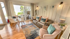 Un salon moderne comprenant un canapé, des fauteuils, une table basse et un coin repas avec une table et des chaises.