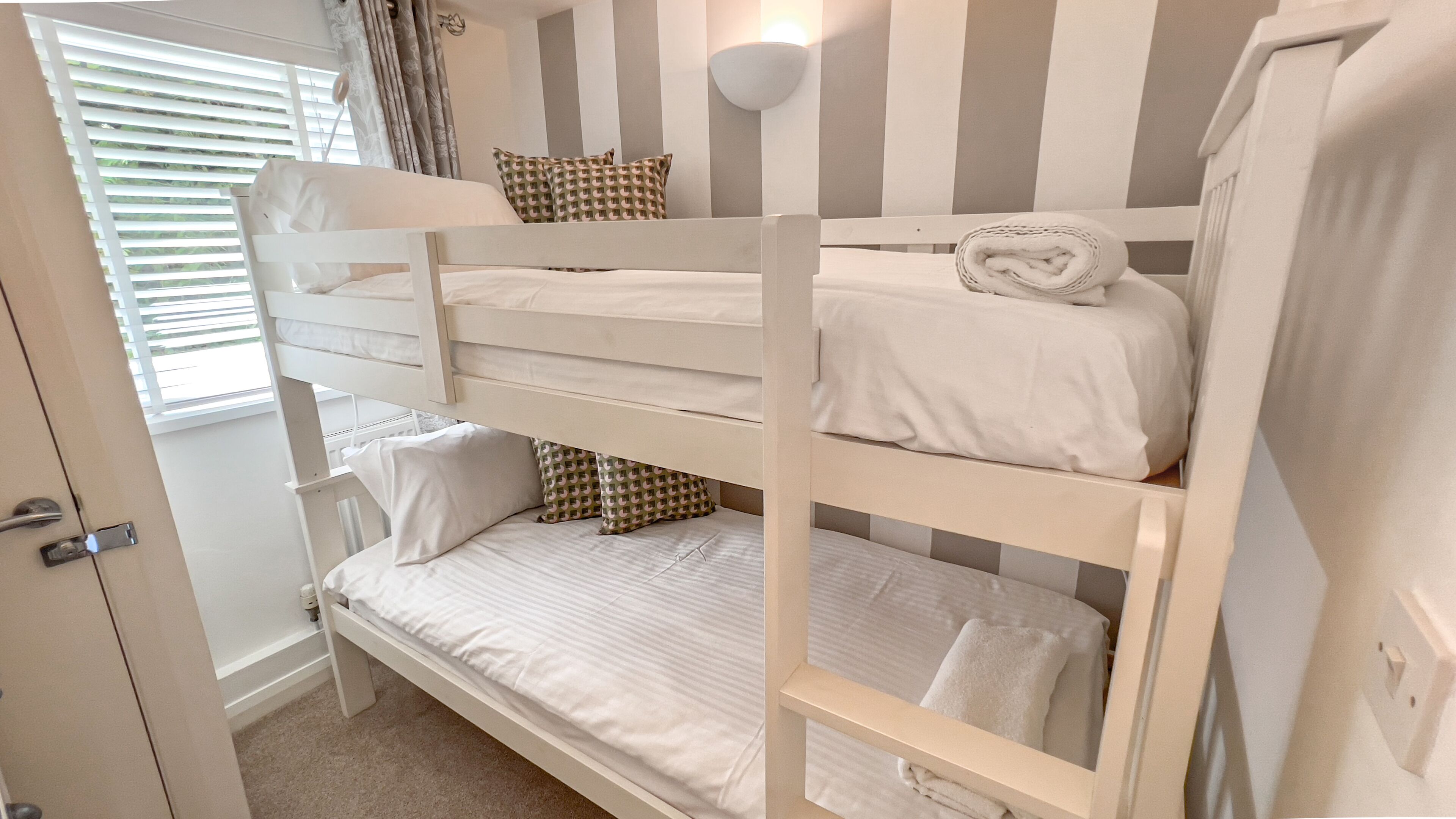 Una camera con letto a castello, biancheria bianca e pareti a righe.
