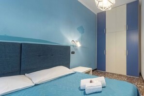 A bedroom with a bed, a nightstand, a wardrobe, and a wall-mounted light fixture.