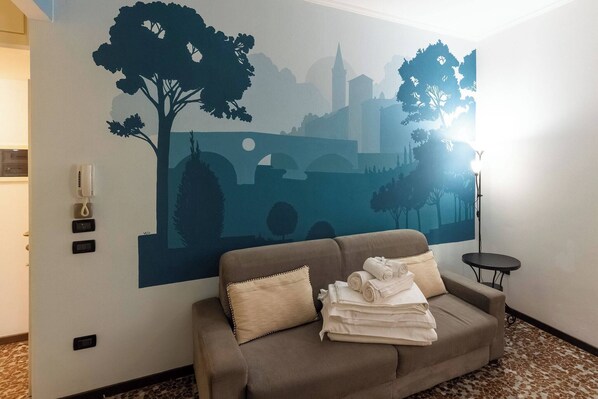 Quarto com sofá, telefone na parede e luminária.