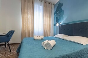 Quarto de hotel com uma cama, uma cadeira e uma parede com um mural de árvore.