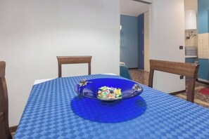 Uma mesa de jantar com toalha xadrez, duas cadeiras e uma tigela decorativa com doces.