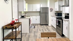 Une cuisine moderne avec des armoires blanches, des appareils en acier inoxydable et un banc en bois.