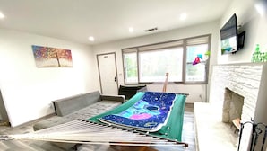 Une pièce avec un hamac servant de lit, une cheminée, un téléviseur et un tableau au mur.
