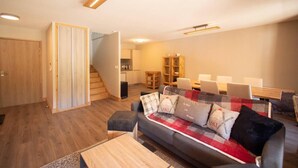A modern living room with a sofa, coffee table, and a staircase leading to a kitchen. - 380m from shops, 4th floor, view mountain, balcony, parking, ski locker, 85m², Valmorel (Les Avanchers-Valmorel)