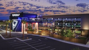 Ein modernes TopGolf-Gelände mit auffälliger Beschilderung, mehreren Ebenen und Außenbereichen mit Sitzmöglichkeiten.