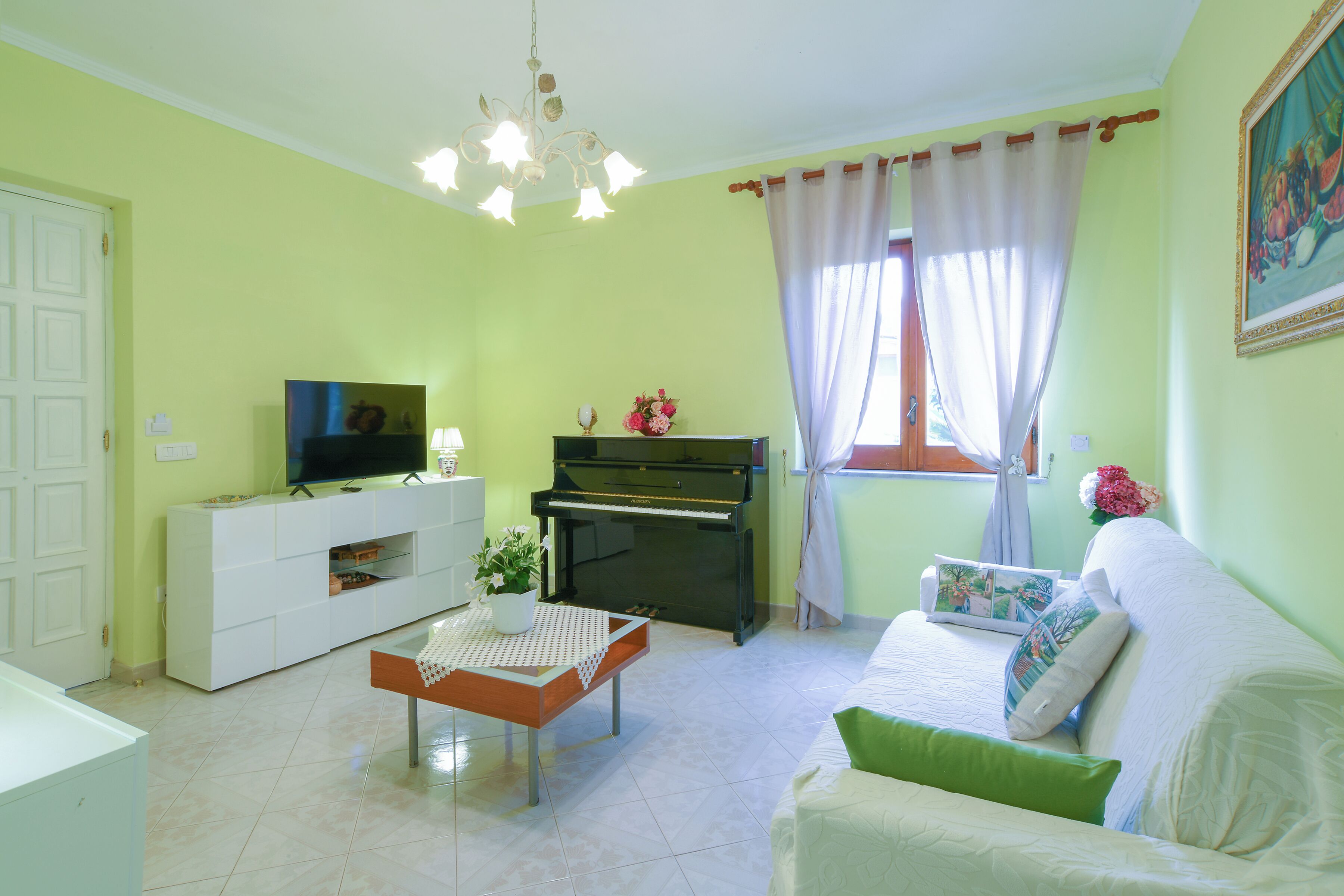 A living room with a piano, a television, and a sofa.